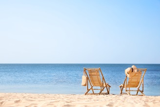 Zwei Liegestühle aus Holz am Strand