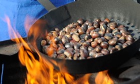 Pfanne über dem Feuer mit gebratenen Kastanien
