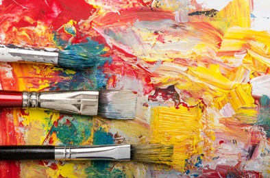 Drei Pinsel. Der Hintergrund ist bunt. 